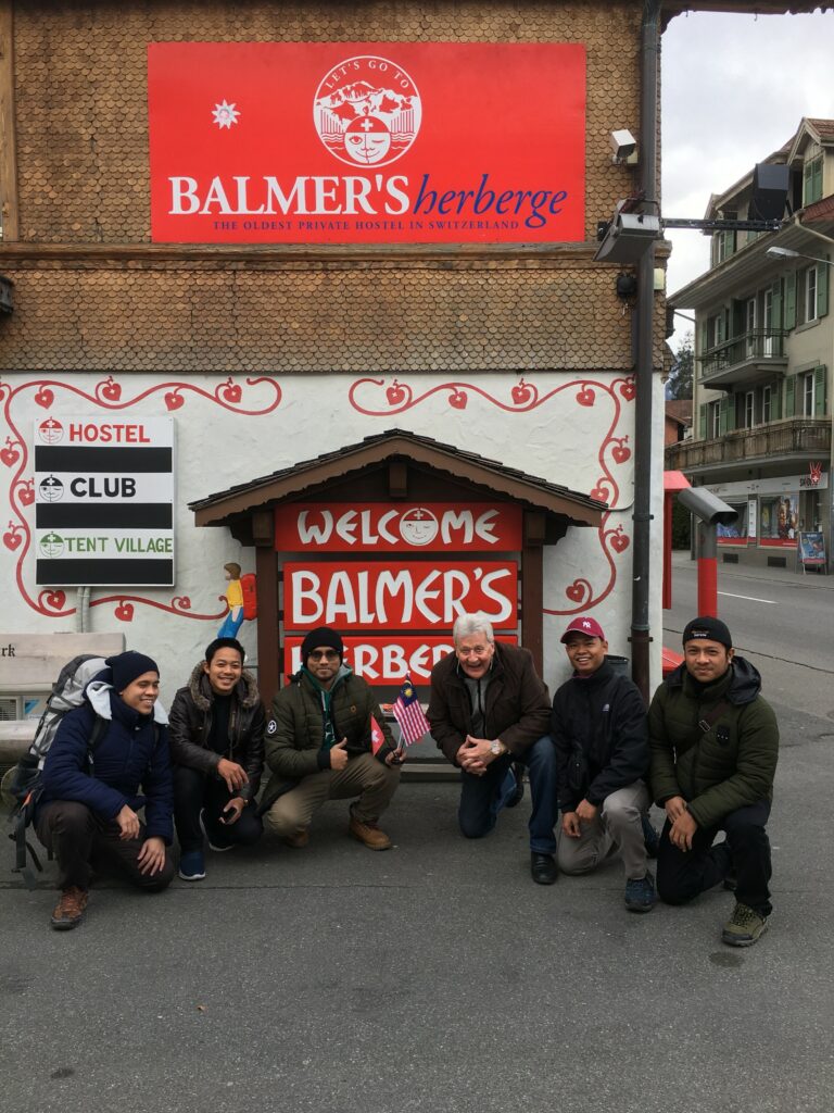 six people posing in front of balmers hostel sign